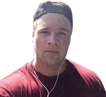 Lähikuva nuoresta miehestä, jolla on päässään lippalakki ja korvissa kuulokkeet, punaisessa paidassa, mustalla taustalla.