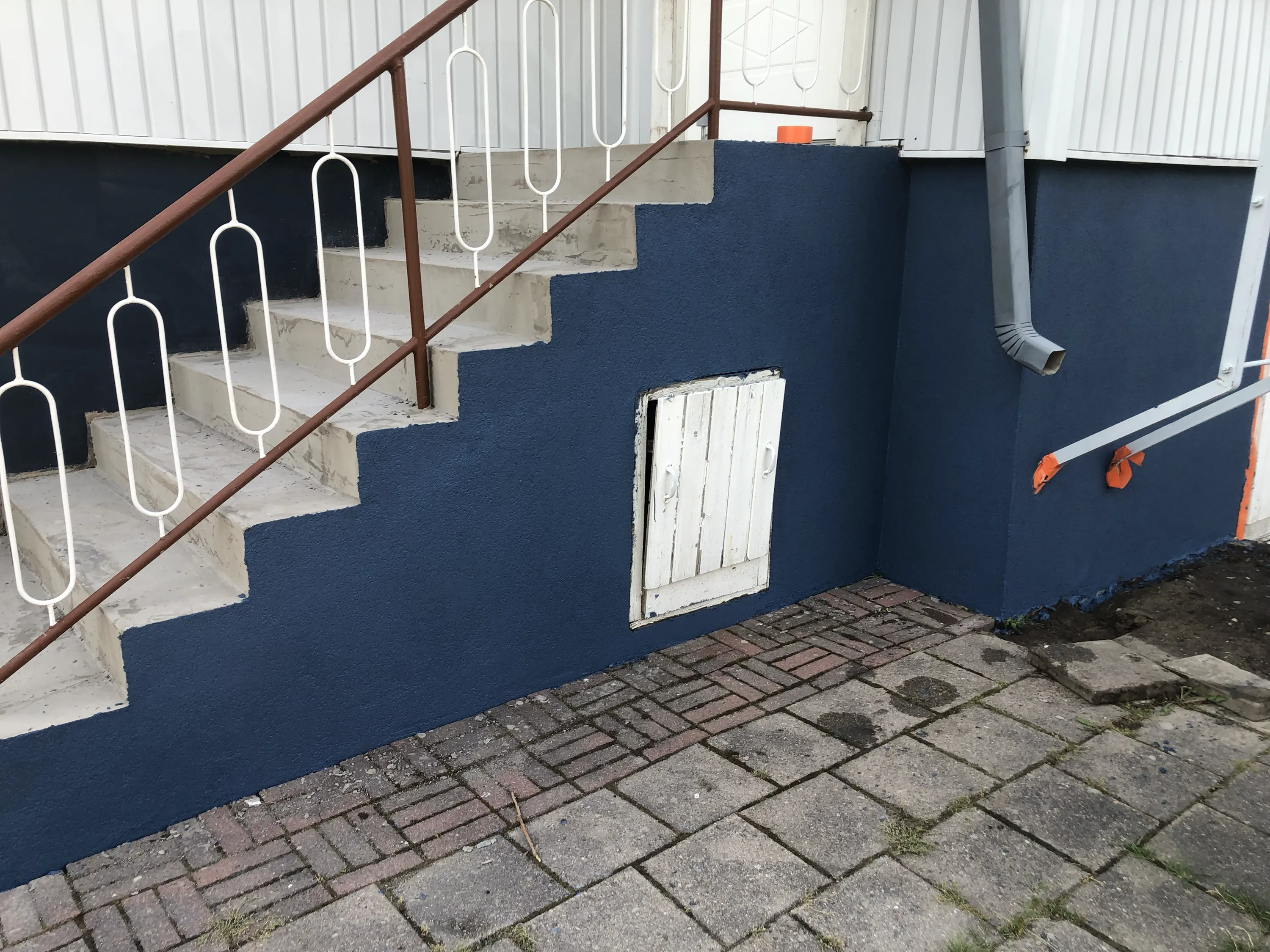 Ulkoportaikko, sininen seinä, valkoinen ovi.